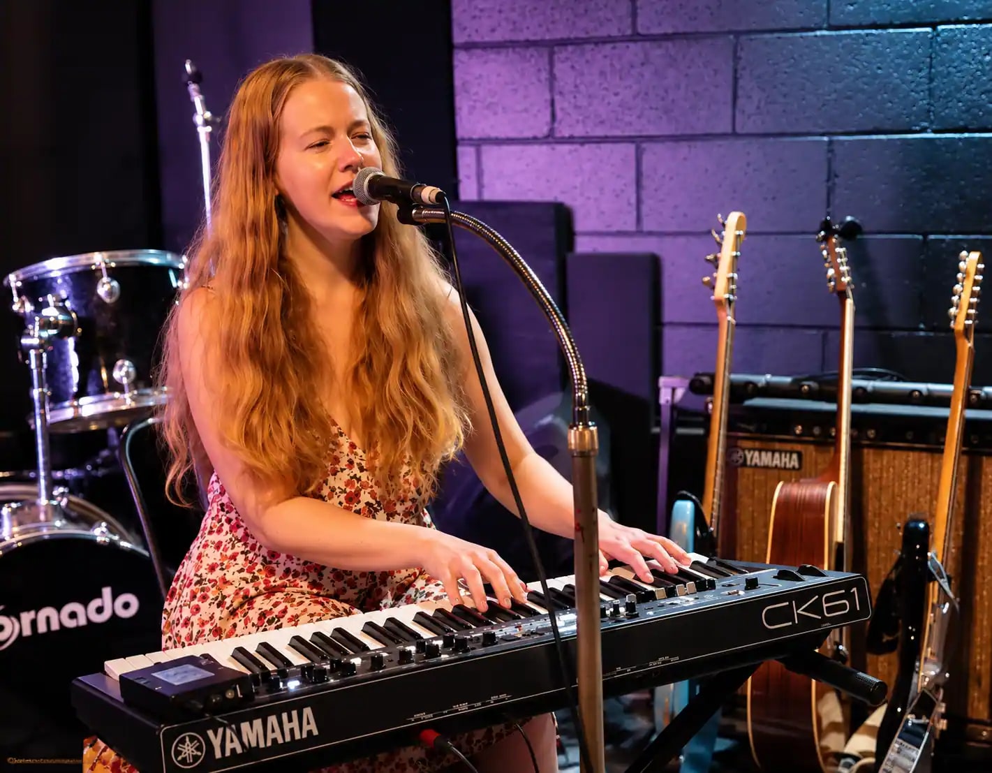 Jess Martyn mid-song at her keyboard, hands on the keys, under stage lighting at a Brisbane venue