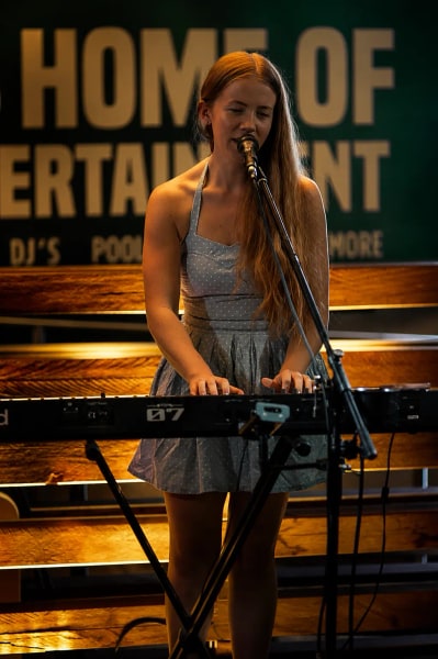 Jess Martyn playing keys and singing under warm gold stage light