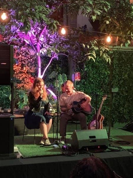 Jess Martyn performing at an outdoor venue with guitarist