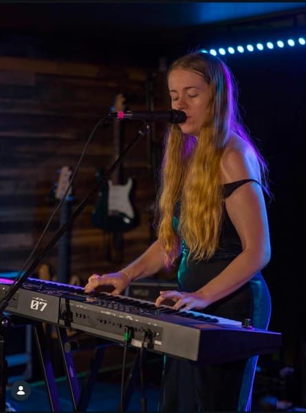 Jess Martyn singing at her keyboard under stage lights